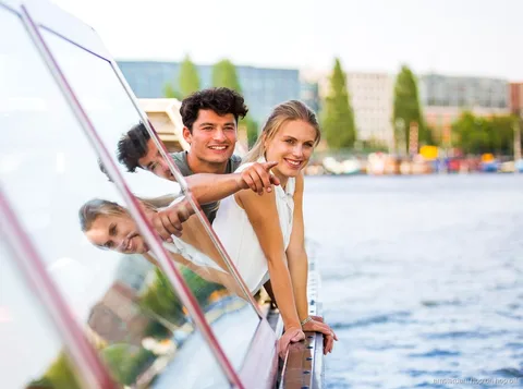 Passengers on the Amsterdam hop-on hop-off boat passing historic canal houses