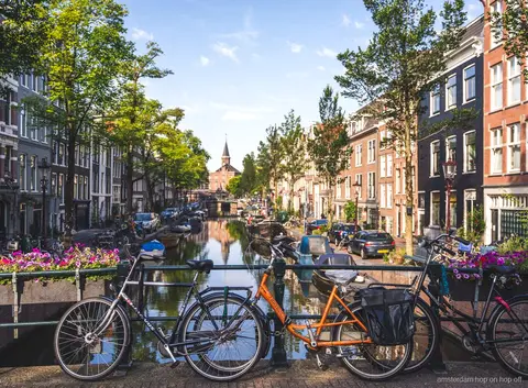 Guide führt eine Amsterdam Stadtführung zu Fuß an Grachtenhäusern vorbei